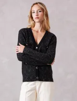 Cardigan de punto con textura tipo tweed en color negro con destellos dorados. Presenta escote en V, cierre frontal con botones metálicos decorativos y bolsillos frontales con solapa. Posee terminaciones acanaladas en cuello, puños y ruedo.