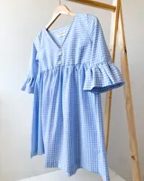 Vestido corto celeste y blanco con estampado de cuadrillé, escote en V, mangas 3/4 con volados y botones decorativos.