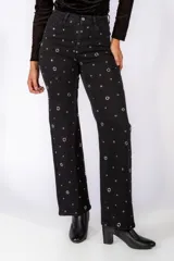 Jean de corte recto y tiro medio, color negro, con detalle de tachas metálicas circulares distribuidas por toda la prenda.