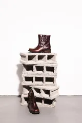 Botas cortas de cuero color marrón óxido con hebillas y arnés metálico.