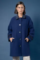Tapado de paño azul con cuello camisero en contraste, cierre frontal de botones y bolsillos laterales. Presenta puños con detalle en contraste.