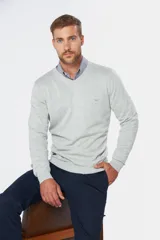 Suéter de tejido fino color azul marino, con cuello en V y manga larga. Presenta un pequeño logo bordado en el pecho.