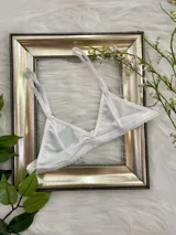 Bralette blanco de lycra con corte triangular, breteles regulables y cierre de gancho en la espalda.