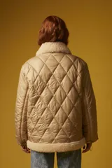 Campera puffer color beige con diseño acolchado de rombos, cuello y solapa de sherpa color crema, cierre frontal con cremallera dorada, bolsillos laterales con solapa marrón y puños elásticos.