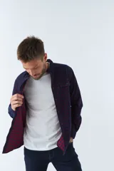 Camisa de manga larga confeccionada en pana de algodón con estampado de cuadros en tonos azul y bordó. Presenta cuello clásico, cierre frontal con botones y ajuste regular.