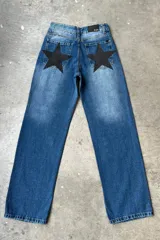 Jean de mezclilla azul de corte recto y tiro medio, con un gran parche negro en forma de estrella en el bolsillo trasero.