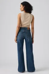 Jeans de denim azul de corte amplio y bota ancha, tiro medio, con efecto ligeramente lavado en las piernas y diseño clásico de cinco bolsillos.