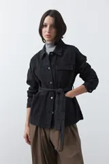 Sobrecamisa de jean color negro con silueta relajada, cuello camisero, cierre frontal con botones metálicos, bolsillos frontales y cinturón ajustable en la cintura.
