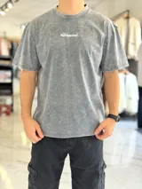 Remera oversize gris con efecto acid wash, de mangas cortas y cuello redondo, con estampado tipográfico blanco en la espalda.