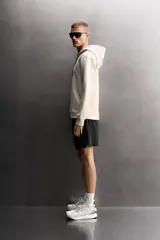 Sudadera de hombre Zara Athleticz de ajuste relajado (relaxed fit), color marrón, confeccionada en tejido técnico compacto con mezcla de algodón y elasticidad. Cuenta con cuello con capucha ajustable con cordones negros, manga larga, bolsillo frontal tipo canguro con un pequeño bolsillo termofijado con cierre, y acabados con rib en puños y cintura.