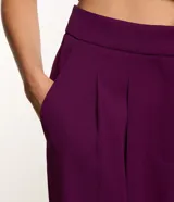 Pantalón jogger de tiro alto confeccionado en crepé color violeta. Presenta pliegues frontales, bolsillos laterales tipo cuchillo y puños elásticos en los tobillos.