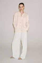 Camisa de mezcla de viscosa, color beige con rayas verticales rosadas, cuello solapa, manga larga con puños anchos, bajo redondeado y cierre frontal con botones.