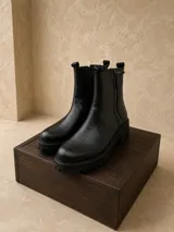 Botas de caña media con textura tipo crocco, color negro, con suela track gruesa y cierre lateral.