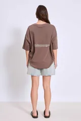 Remera de corte oversize color blanco, con cuello redondo y mangas cortas. Presenta un pequeño estampado minimalista en el pecho con motivos playeros.