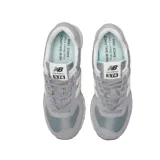 Championes urbanos New Balance modelo 574, color gris con detalles en blanco y crema. Confeccionados en una combinación de gamuza y malla, presentan el logo N característico en los laterales y entresuela con tecnología ENCAP para mayor soporte y confort.
