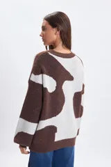Buzo de punto con diseño jacquard de manchas abstractas en tonos marrón y crema, de corte holgado, cuello redondo y mangas largas con puños ajustados.