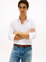 Camisa de twill blanca de manga larga, con cuello flexible, cierre frontal de botones y detalles distintivos de la marca Tommy Hilfiger.