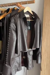 Camisa de cuero ovino color chocolate, con diseño de cutouts entrelazados a lo largo de las mangas y cierre frontal con broches forrados.
