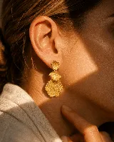 Aros colgantes dorados con diseño de tres piezas superpuestas en forma de abanico o concha con textura estriada.