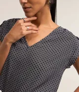 Blusa de crepé con estampado geométrico en blanco y negro, escote en V y mangas cortas sin sisa con detalle fruncido en los hombros.