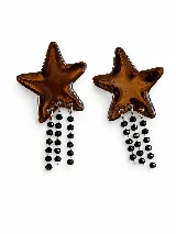 Aros de acrílico con forma de estrella color marrón translúcido, con tres tiras colgantes de cadena decoradas con cuentas negras facetadas.