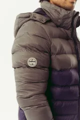 Campera puffer de abrigo con diseño bicolor, gris en la parte superior y violeta oscuro en la inferior. Cuenta con cierre frontal completo, capucha desmontable, bolsillos laterales con cierre y logo estampado en el pecho.
