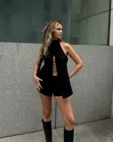 Top negro con cuello alto, abertura frontal con detalle de cadena plateada y corte irregular.