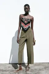 Pantalón de lino negro, de tiro alto, con bolsillos delanteros de vivo, pernera recta y cierre frontal con cremallera, botón interior y gancho metálico.