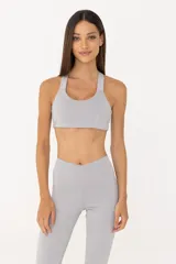 Top deportivo gris claro de poliéster y elastano, con espalda descubierta, breteles finos y banda elástica inferior.