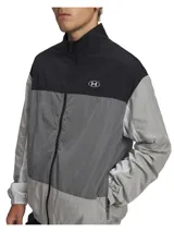 Campera deportiva Under Armour modelo Icon Woven Track FZ, con diseño color-block en tonos negro, gris oscuro y gris claro. Cuenta con cuello alto, cierre frontal completo, bolsillos laterales con cremallera y puños y dobladillo elásticos.