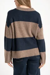 Sweater de punto con cuello polo y cierre frontal de tres botones. Presenta un diseño de corte oversize, mangas largas y textura acanalada.