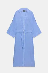Vestido midi de cuello solapa con escote en pico y mangas tres cuartos ajustables con trabilla. Cuenta con bolsillos delanteros de plastrón, bolsillos laterales ocultos en costura, cierre frontal con botones y cinturón ajustable del mismo tejido con hebilla metálica circular.