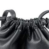 Cartera tipo balde de símil cuero graneado color negro, con cierre de cordón ajustable y correa larga regulable con hebilla metálica. Presenta el logo de la marca grabado en el frente.