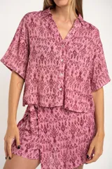Camisa de manga corta con estampado abstracto en tonos rosa y borgoña. Tiene cuello camisero, cierre frontal con botones y corte oversize.