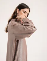 Camisa oversized con terminación metalizada color gris plomo. Tiene botones a tono en el delantero, largo por debajo de la cadera y tajos a los costados.