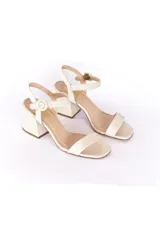 Sandalias de taco ancho alto confeccionadas en cuero color off-white, con tira delantera simple, tira en el empeine y correa al tobillo con hebilla forrada.