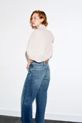 Jeans de tiro alto con corte culotte y pernera ancha. Presenta bolsillos de plastrón en el frente con detalle de pespuntes decorativos en forma de onda y costuras verticales a lo largo de la pierna. Cierre frontal con cremallera y botón metálico.