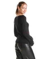 Blusa de punto negra con escote en V y detalle metálico en el pecho. Presenta mangas largas con puños decorados con apliques de strass y plumas negras.