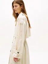 Gabardina larga color beige claro, con corte oversize, solapas con muescas, cierre de botones y cinturón anudable.