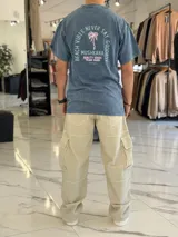 Remera oversize gris con efecto lavado ácido, manga corta y estampa en la espalda con texto y diseño de palmera.