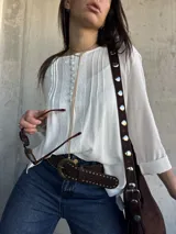 Blusa oversize de color blanco con diseño romántico y bohemio, confeccionada con detalles de encaje y botones forrados en el frente. Cuenta con mangas largas.