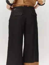 Pantalón sastrero de corte ancho, color beige con rayas verticales blancas y detalles de costuras pespunteadas.