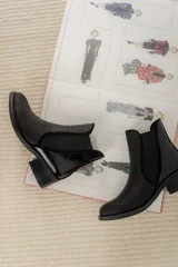 Botinetas de cuero color marrón con diseño tipo chelsea, con paneles laterales elásticos y detalle de cuero texturizado con acabado metalizado en el talón. Poseen taco bajo cuadrado y terminación redondeada.