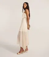 Vestido midi de encaje color crudo, con escote strapless, superposición en el busto, falda asimétrica y forro interno.