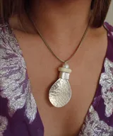 Collar plateado con dos gargantillas rígidas y un colgante con forma de lágrima con textura de alpaca.