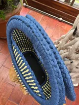 Bolso tejido a crochet con hilo de trapillo en color azul y beige con flecos naranjas y asas circulares rígidas.