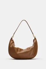 Bolso de hombro de diseño slouchy en color marrón, con asa de hombro ajustable mediante mosquetones metálicos dorados y cierre superior de cremallera.