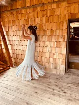 Vestido tejido color gris con hilado levemente brillante, corte oversized y flecos en el ruedo.