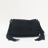 Bandolera negra de gamuza con solapa frontal y flecos laterales largos. Cuenta con herrajes metálicos en tono bronce.