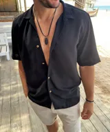 Camisa de fibrana negra de manga corta, con cuello solapa y cierre frontal de botones claros.